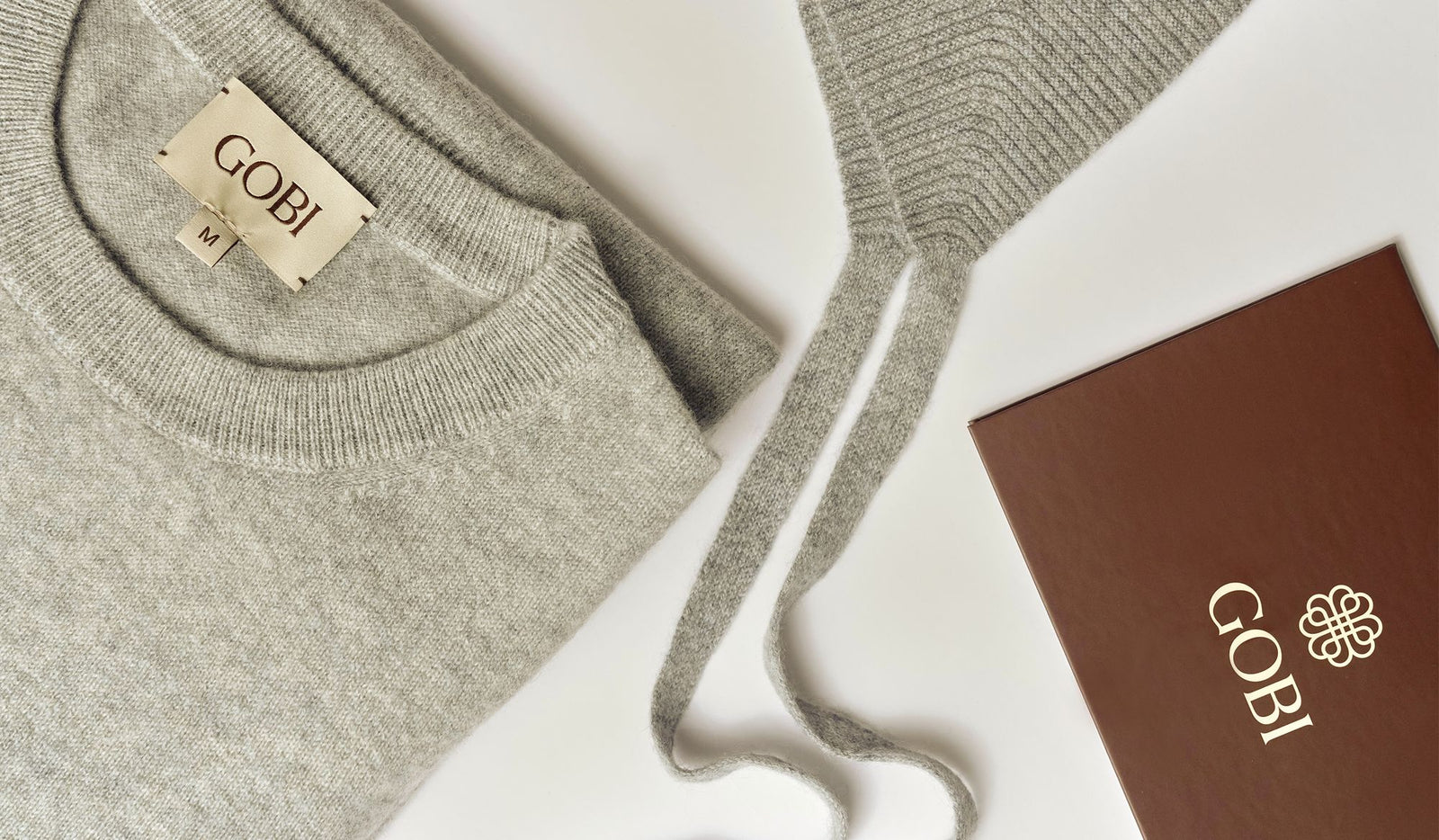 Gray sweater with a Gobi label and box on a white background