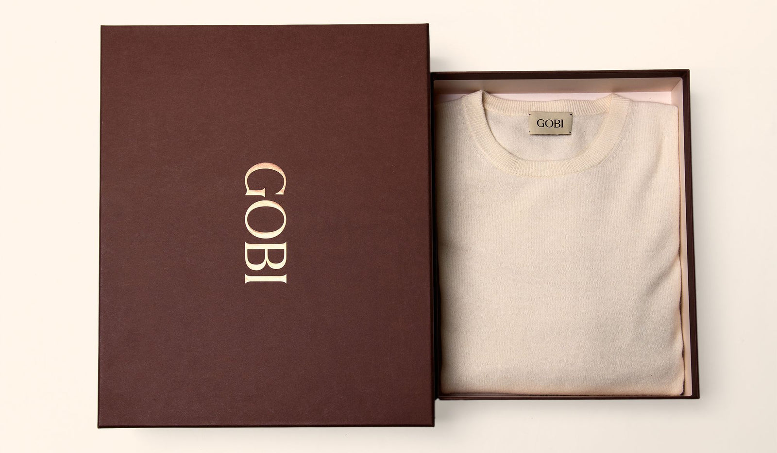 Beige t-shirt in an open brown box with 'Gobi' branding on a white background