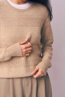 Model wearing affordable cashmere sweater in beige with pointelle stripes and ribbed cuffs, front detail view
