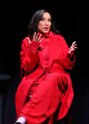 Celebrities wearing cashmere: Robin Thede seated in a red double-breasted long coat, front view