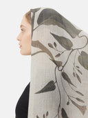 Model wearing a warm cashmere scarf with leaf print draped over her head, side view