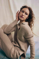 Model in beige pointelle cashmere polo sweater and ribbed pants, self esteem clothing seated pose