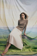 Model in light brown ribbed boat-neck sweater and cream midi skirt showing year-round cashmere wear, front view