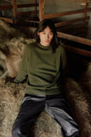 Model in green crewneck cashmere sweater and dark pants, a capsule wardrobe sweater styled front view