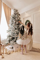 GOBI Cashmere 2023 recap: woman and child in cream knitwear decorating a snowy holiday tree with GOBI gift boxes