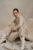 Model in beige patterned turtleneck sweater and wide pants showing old money style cashmere, seated front view