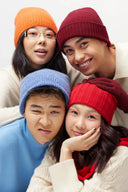 Four models wearing ribbed cashmere accessories gifts: orange, burgundy, blue and red hats with red gloves