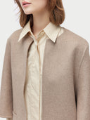 Beige crew neckline poncho over a cream shirt on a plain background #color_taupe