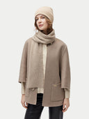 woman wearing together a beige beanie, scarf and poncho #color_beige