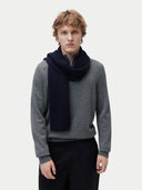 Person wearing a gray sweater and black scarf on a white background #color_navy-blazer