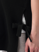 Close-up of a person wearing a black top with a tie detail. #color_black