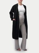 Person wearing a black cardigan, white top, and gray maternity pants on a white background #color_dawn-blue