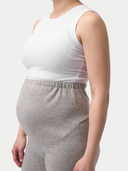 Person wearing a white sleeveless top and gray maternity pants on a plain background #color_dawn-blue
