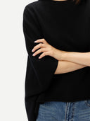 close up of a black poncho and blue jeans on a light gray background #color_black