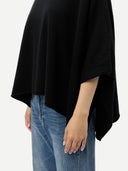 close up of a black poncho and blue jeans on a white background #color_black