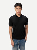 Man wearing a black polo shirt and blue jeans on a white background
