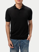 Person wearing a black polo shirt and blue jeans on a white background