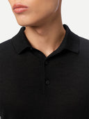 Close-up of a person wearing a black polo shirt against a neutral background