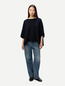 front view of a person wearing a dark navy poncho and blue jeans on a white background #color_navy-blazer