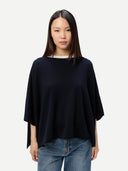 Woman wearing a navy blue poncho over a white shirt and jeans on a light gray background #color_navy-blazer