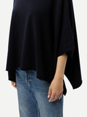 Person wearing a navy poncho and blue jeans on a white background #color_navy-blazer