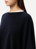close up of a navy blue poncho worn by a person on a white background #color_navy-blazer