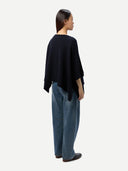 back view of a woman wearing a navy poncho and blue jeans on a white background #color_navy-blazer