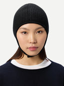 close up side view of a woman wearing a black knitted aviator cap with buttoned , navy poncho on a light gray background #color_black