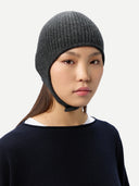 close up side view of a woman wearing a dark gray knitted aviator cap with buttoned , navy poncho on a light gray background #color_charcoal