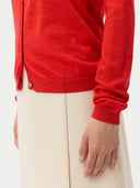 close up of a red cardigan worn by a person on a white background #color_red