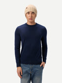 Man wearing a navy sweater, beige beanie, and jeans on a white background. #color_beige