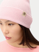 Person wearing a pink beanie with a logo on a white background.
