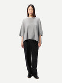 Woman wearing a gray poncho and black pants on a white background #color_high-rise