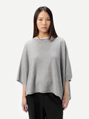 Woman wearing a gray poncho over a black outfit on a white background #color_high-rise