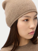 close up of a woman wearing a beige knit beanie against a white background #color_taupe