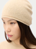 close up of a woman wearing a beige beanie against a plain background #color_beige