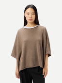 Woman wearing a brown poncho over a white shirt on a white background