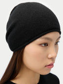 close up of a woman wearing a black beanie against a white background #color_all