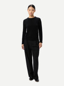 Front view of a person wearing a black sweater and pants on a white background #color_black
