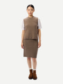 Woman wearing a brown knitted vest and skirt set on a white background.