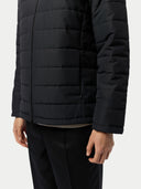 close up of a black puffer jacket worn by a person on a white background  #color_black