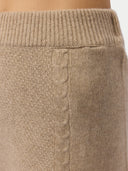 Close-up of beige knitted pants with cable pattern #color_warm-grey