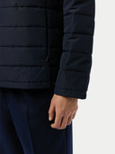 close up of navy blue puffer jacket worn by a person on a white background #color_navy-blazer