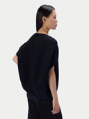 A model shown from the back wearing a black short-sleeve knit top and matching black bottoms against a light gray studio background.