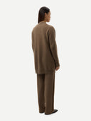 A model shown from the back wearing a matching brown knit sweater and wide-leg trousers set against a plain light gray background.