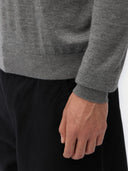 Close-up of a person wearing a gray sweater with a black background #color_dim-gray