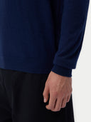 close up of a person wearing a navy long sleeve sweater and black pants on a white background #color_mood-indigo