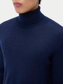 close up of a navy blue turtleneck sweater worn by a person on a light gray background #color_mood-indigo