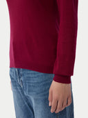 close up of a person wearing a burgundy sweater and blue jeans on a white background #color_bordeaux