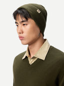 Person wearing a green knit beanie and sweater with a beige collar against a white background #color_avocado